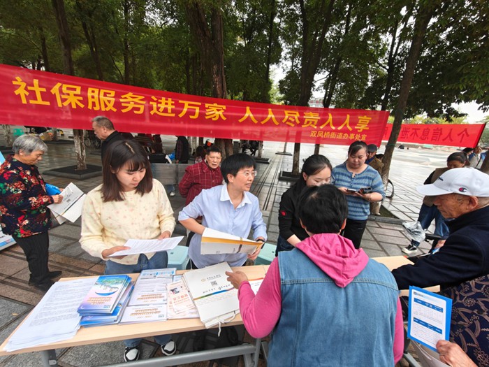 宣传台前，工作人员热情向居民发放医保宣传彩页。王思婕摄